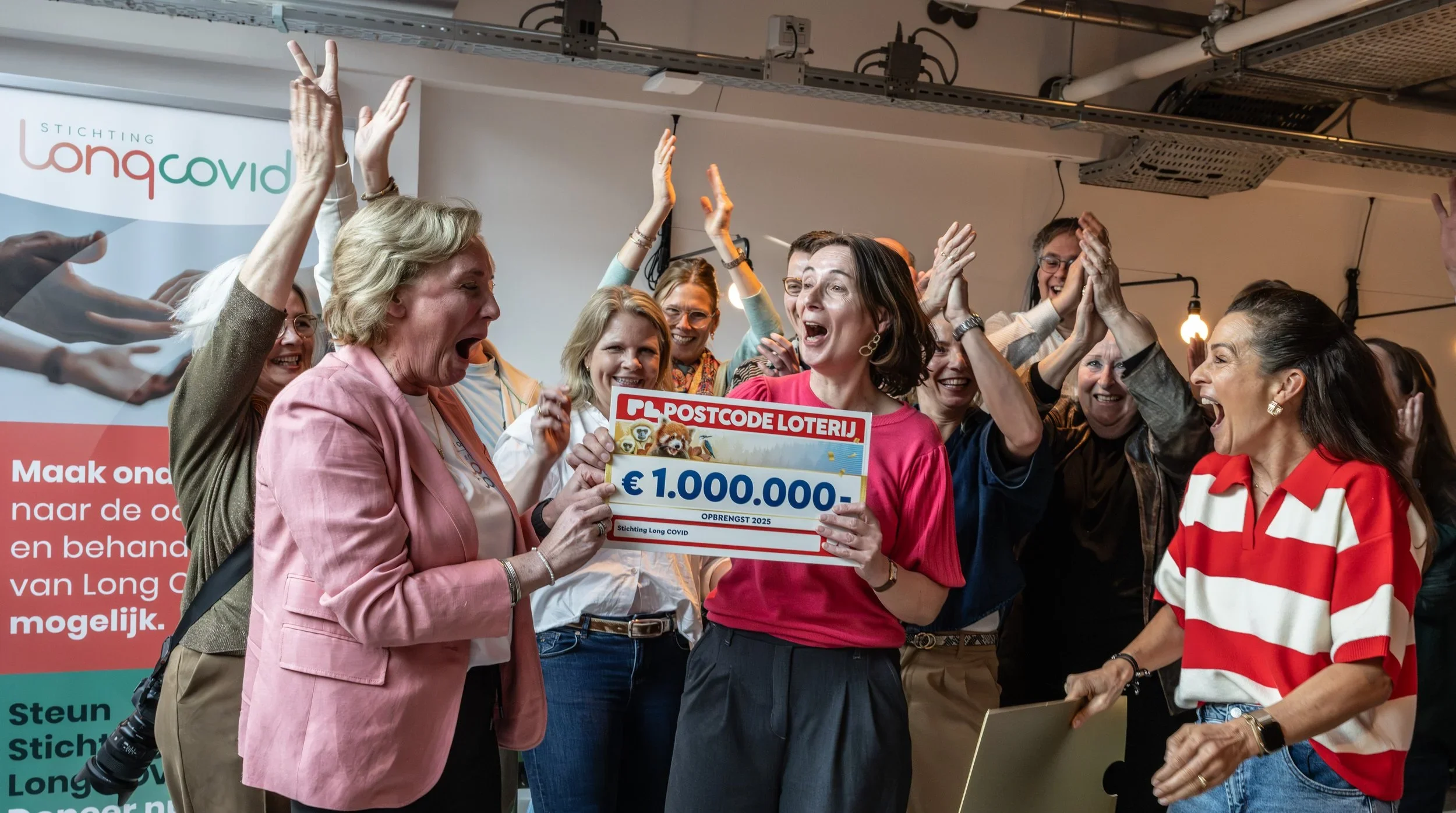Oprichters Ellen en Annelies nemen cheque van Postcode Loterij in ontvangst.